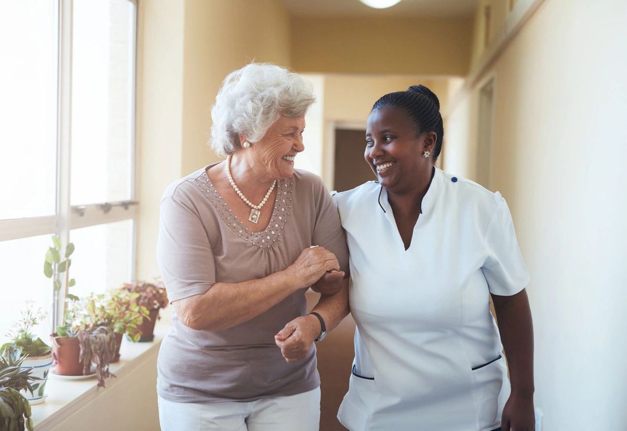 A nurse and an older woman are smiling together.