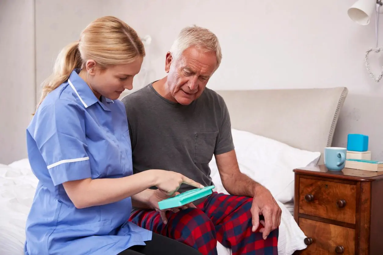 A nurse is helping an older man with his medical equipment.